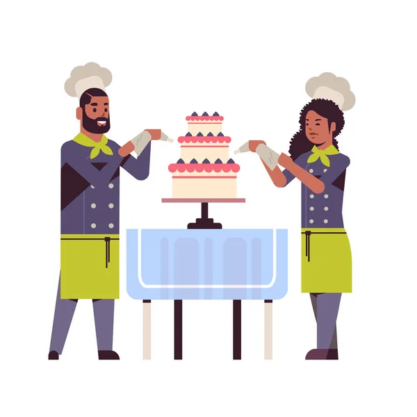 Cooks couple professional pastry chefs decorating tasty wedding cream cake african american woman man restaurant workers in uniform cooking food concept — Stock Vector