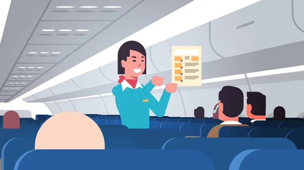 Azafata explicar para los pasajeros instrucciones tarjeta asistente de vuelo femenino concepto de demostración de seguridad moderno avión bordo interior horizontal retrato — Vector de stock