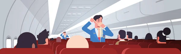 steward explaining for passengers how to use oxygen mask in emergency situation male flight attendants safety demonstration concept modern airplane board interior horizontal