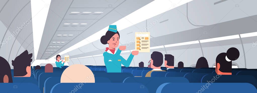 stewardess explaining for passengers instructions card female flight attendants safety demonstration concept modern airplane board interior horizontal portrait