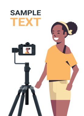 Afrikalı Amerikalı kadın blogcu dijital kamerayla video blogu kaydediyor tripoda canlı sosyal medya blog konsepti portresi dikey fotokopi alanı