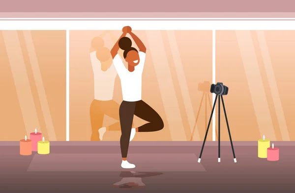 Yoga yapan kadın blogcu spor egzersizleri yapıyor. Çevrimiçi video kaydediyor. Üç ayaklı, sağlıklı bir yaşam tarzı. — Stok Vektör