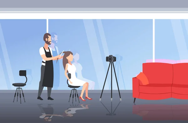 Hairdresser blogger making hairstyle cutting hair tips of woman customer man recording online video with camera on tripod blogging concept modern beauty salon interior full length horizontal — Stock vektor