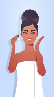 Kirpiklerine siyah maskara süren Afro-Amerikan kız makyaj yapıyor. Makyaj prosedürü, konsept portresi dikey.