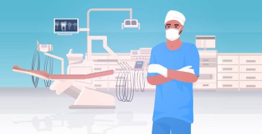 Koruyucu maskeli erkek dişçi ve eldivenler katlanmış hastane kliniği çalışanı üniforma sağlık hizmetleri konsepti modern dişçi kliniği iç tasviri yatay portre