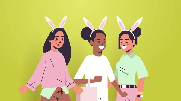 Vrouwen dragen konijnenoren schattig mix race meisjes vieren gelukkig Pasen vakantie — Stockvector