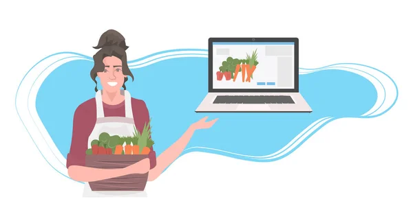 女园丁，篮子里装满了新鲜蔬菜，使用笔记本电脑，网上健康营养食品订单 — 图库矢量图片
