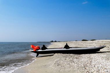 Kumlu bir plaj ve güzel sunlig ile deniz kıyısında şişme kayık