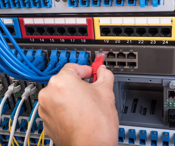 Рука с сетевыми кабелями, подключенными к серверам — стоковое фото