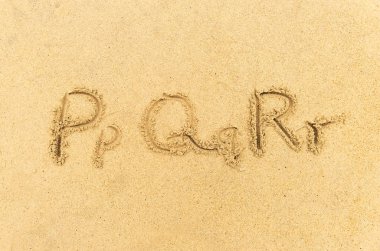 Alfabe harfleri kumsalda el yazısıyla yazılmış.