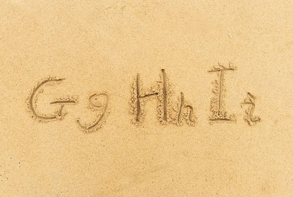 用沙子在沙滩上手写的字母字母 — 图库照片