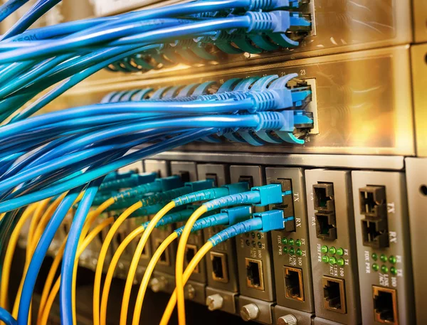 光ポートに接続された光ファイバーケーブルとイーサネットポートに接続されたネットワークケーブル — ストック写真