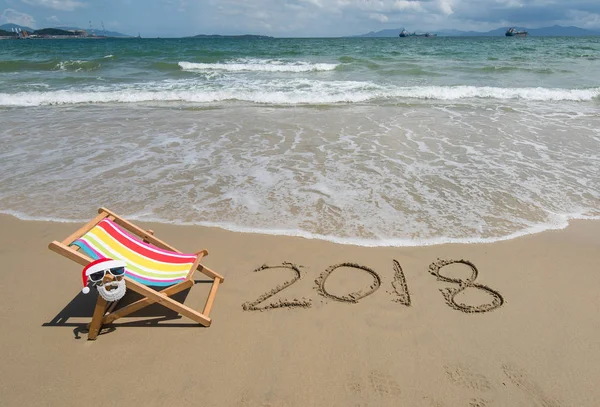 2018, napisane w piasku napisz na tropikalnej plaży. Krzesło składane z San — Zdjęcie stockowe