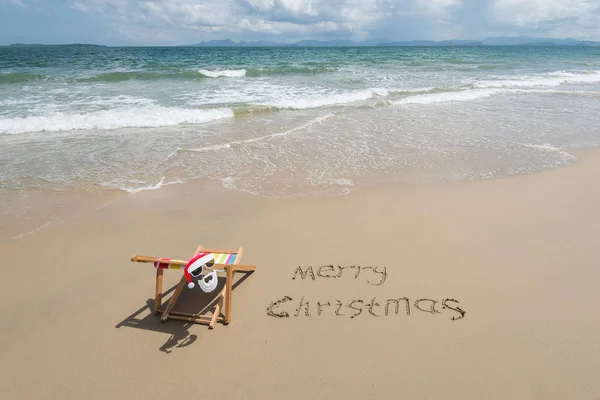 Счастливого Рождества Написанного Песком Кресле Солнцезащитными Очками Санта Клауса — стоковое фото