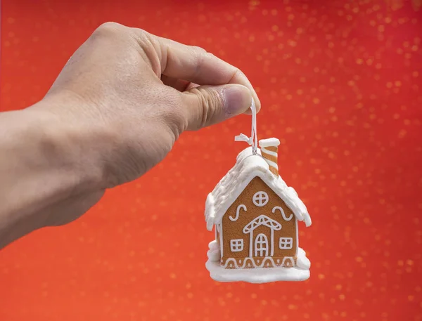 手与圣诞节装饰 姜饼房子的红色背景 — 图库照片