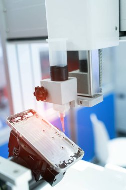 Robot cep telefonu fabrikasına şırınga tutuyor.