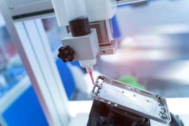 Robot cep telefonu fabrikasına şırınga tutuyor.