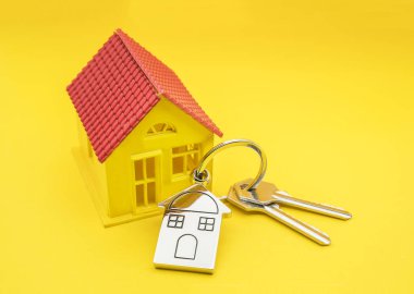 Sarı arka planda ev sembolü ve anahtar zinciri, Gerçek e