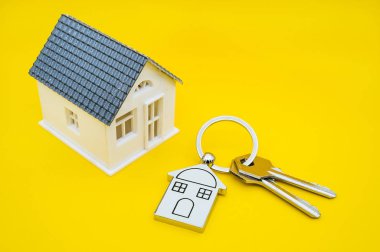 Sarı arka planda ev sembolü ve anahtar zinciri, Gerçek e