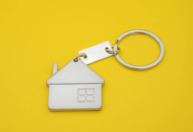 Sarı arka planda ev sembolü ve anahtar zinciri, Gerçek e