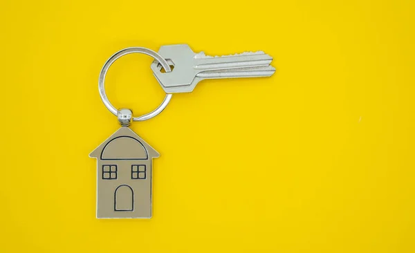 Schlüsselanhänger mit Haussymbol und Schlüsseln auf gelb — Stockfoto
