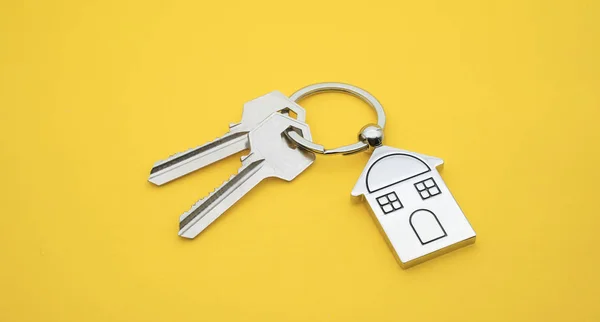 key chain with house symbol and keys on yellow