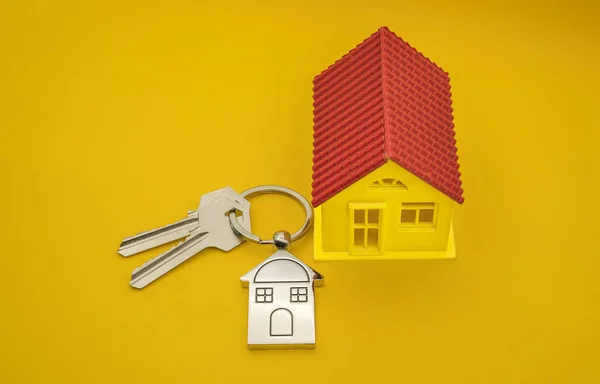 Přívěšek na klíče se symbolem domu a klávesami na žlutém pozadí, Real e — Stock fotografie