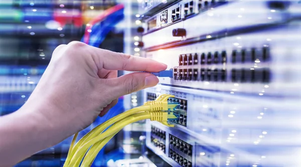 Hand mit Glasfaser-Netzwerkkabeln, die mit Servern in einem Rechenzentrum verbunden sind — Stockfoto
