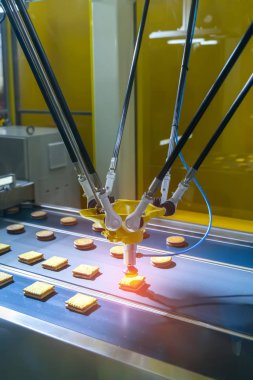 Gıda endüstrisi için bir imalat fabrikasında bisküvi üretiminde konveyör kullanan vakumlu emicilerle otomatikleştirilmiş robot.
