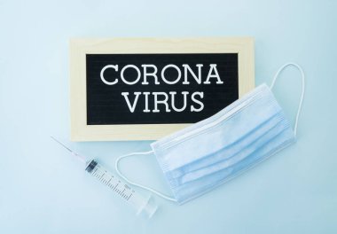 Mavi arka planda Coronavirus harfleri, şırınga, sağlık ve tıbbi konseptin yanında Solunum koruma maskesi.