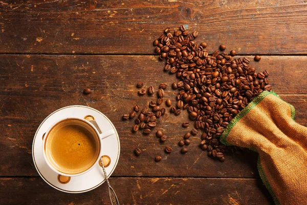Kaffeetasse und Bohnen auf Holztisch — Stockfoto