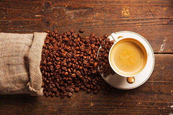 Kaffeetasse und Bohnen auf Holztisch — Stockfoto