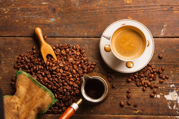 Koffiekopje en bonen op houten tafel — Stockfoto