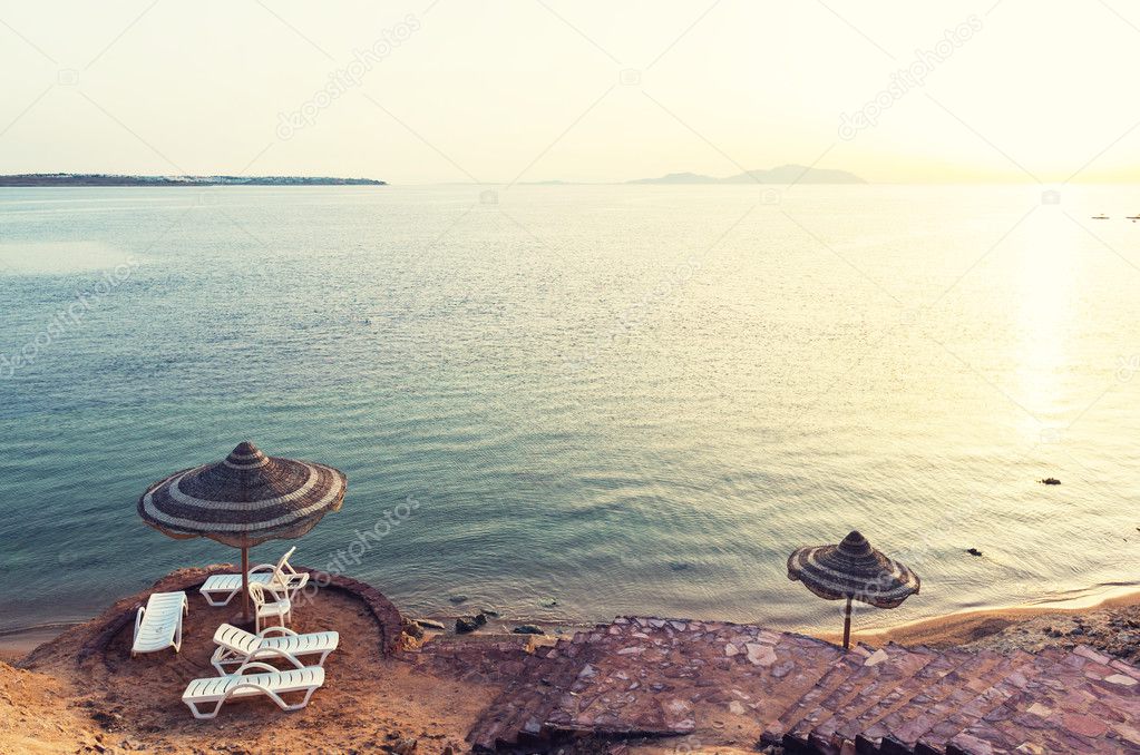 Parasols on the beach in resort of Egypt. Clear waters of Red sea. Popular vacation destination of Europeans.