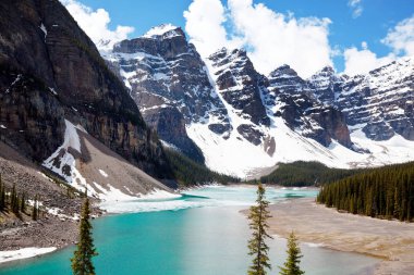 Moraine Gölü 'nün turkuaz suları. Kanada' nın Banff Ulusal Parkı 'nda karla kaplı tepeleri var.