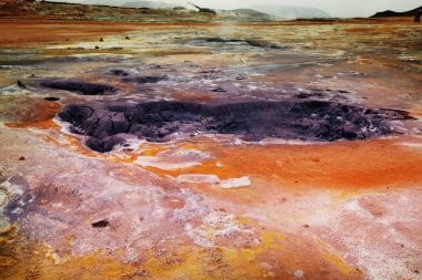 Boiling mud pools in a geothermal landscape in Iceland clipart