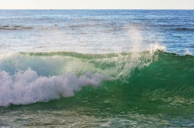 Kumsalda mavi dalga. Bulanık arkaplan ve güneş ışığı lekeleri. Huzurlu doğal arkaplan.