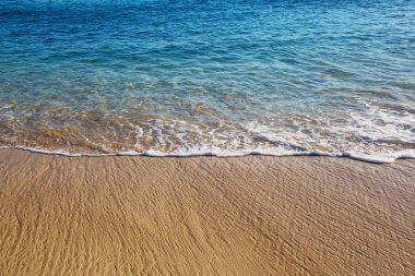 Kumsalda mavi dalga. Bulanık arkaplan ve güneş ışığı lekeleri. Huzurlu doğal arkaplan.