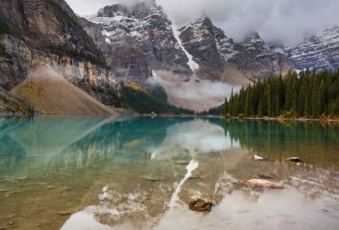 Moraine Gölü 'nün turkuaz suları. Kanada' nın Banff Ulusal Parkı 'nda karla kaplı tepeleri var.