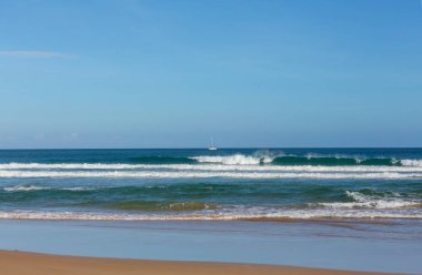 Kumsalda mavi dalga. Bulanık arkaplan ve güneş ışığı lekeleri. Huzurlu doğal arkaplan.