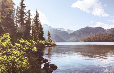 Sakin sulardaki kayaların yansımasıyla dağdaki gölün sakin manzarası..