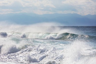 Kumsalda mavi dalga. Bulanık arkaplan ve güneş ışığı lekeleri. Huzurlu doğal arkaplan.