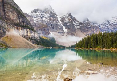 Moraine Gölü 'nün turkuaz suları. Kanada' nın Banff Ulusal Parkı 'nda karla kaplı tepeleri var.