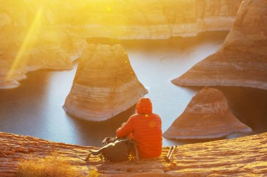 Unusual natural background. Reflection Canyon on Lake Powell, Utah, USA. Inspiring hiking scene-man resting on the beautiful sunset point. clipart