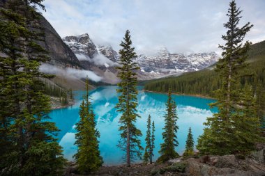 Moraine Gölü 'nün turkuaz suları. Kanada' nın Banff Ulusal Parkı 'nda karla kaplı tepeleri var.