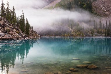 Moraine Gölü 'nün turkuaz suları. Kanada' nın Banff Ulusal Parkı 'nda karla kaplı tepeleri var.