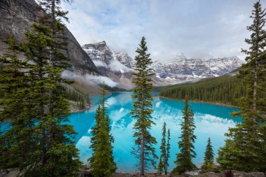 Moraine Gölü 'nün turkuaz suları. Kanada' nın Banff Ulusal Parkı 'nda karla kaplı tepeleri var.