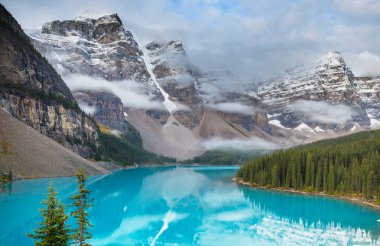 Moraine Gölü 'nün turkuaz suları. Kanada' nın Banff Ulusal Parkı 'nda karla kaplı tepeleri var.