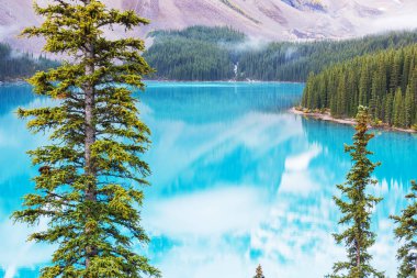 Moraine Gölü 'nün turkuaz suları. Kanada' nın Banff Ulusal Parkı 'nda karla kaplı tepeleri var.