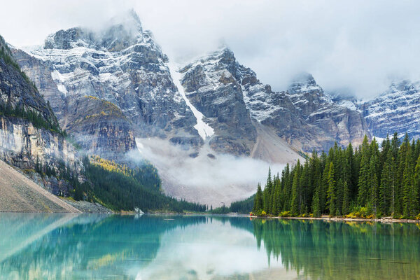 Beautiful turquoise waters of the Moraine lake with snow-covered peaks above it in Banff National Park of Canada